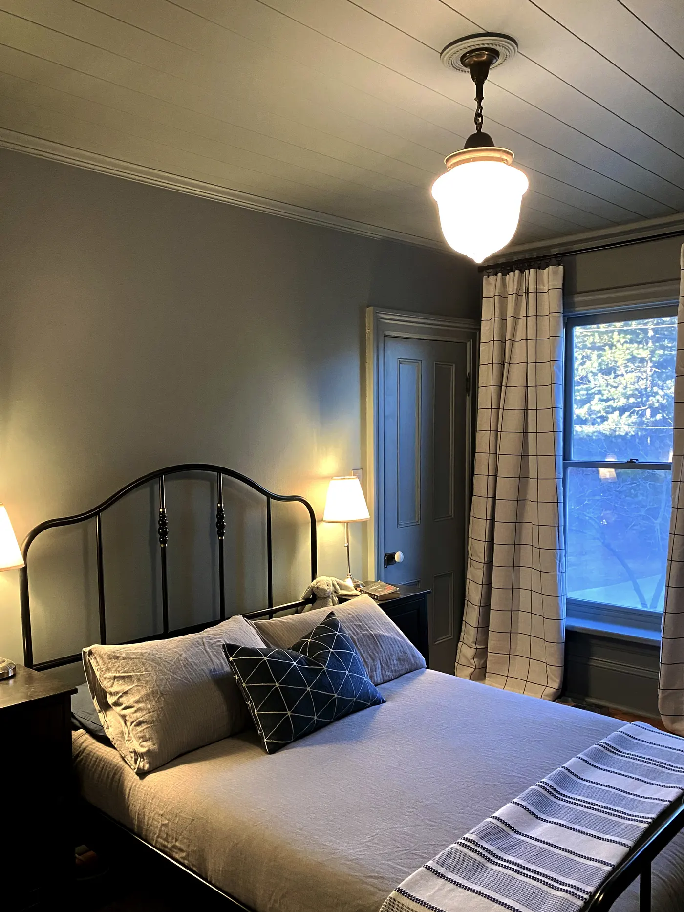 Layered bedroom with iron bed, painted ceiling, tailored curtains, and warm lighting